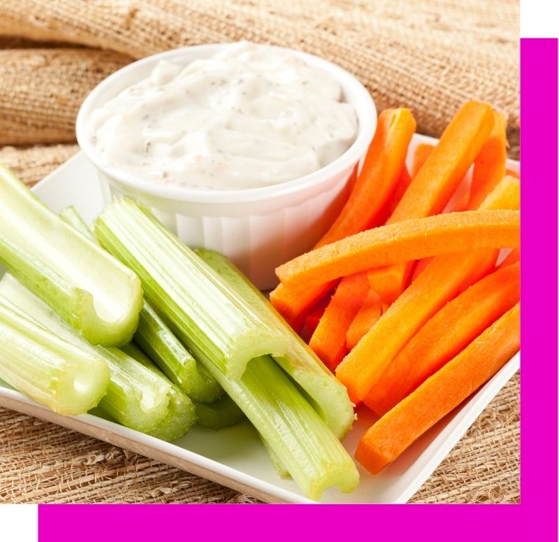 bowl of high protein ranch dip surrounded by carrots and celery
