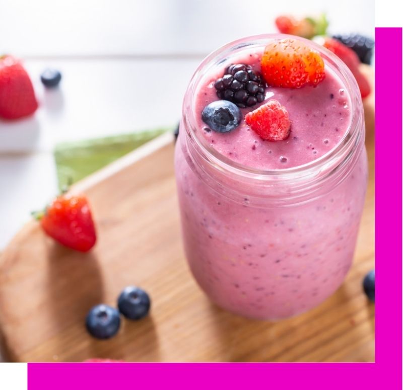 a pink smoothie topped with berries in a jar
